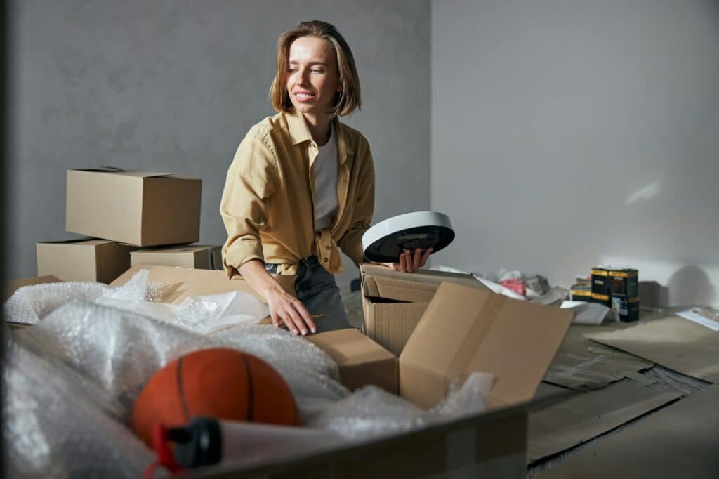 Smiling female seated on the floor among carton packages